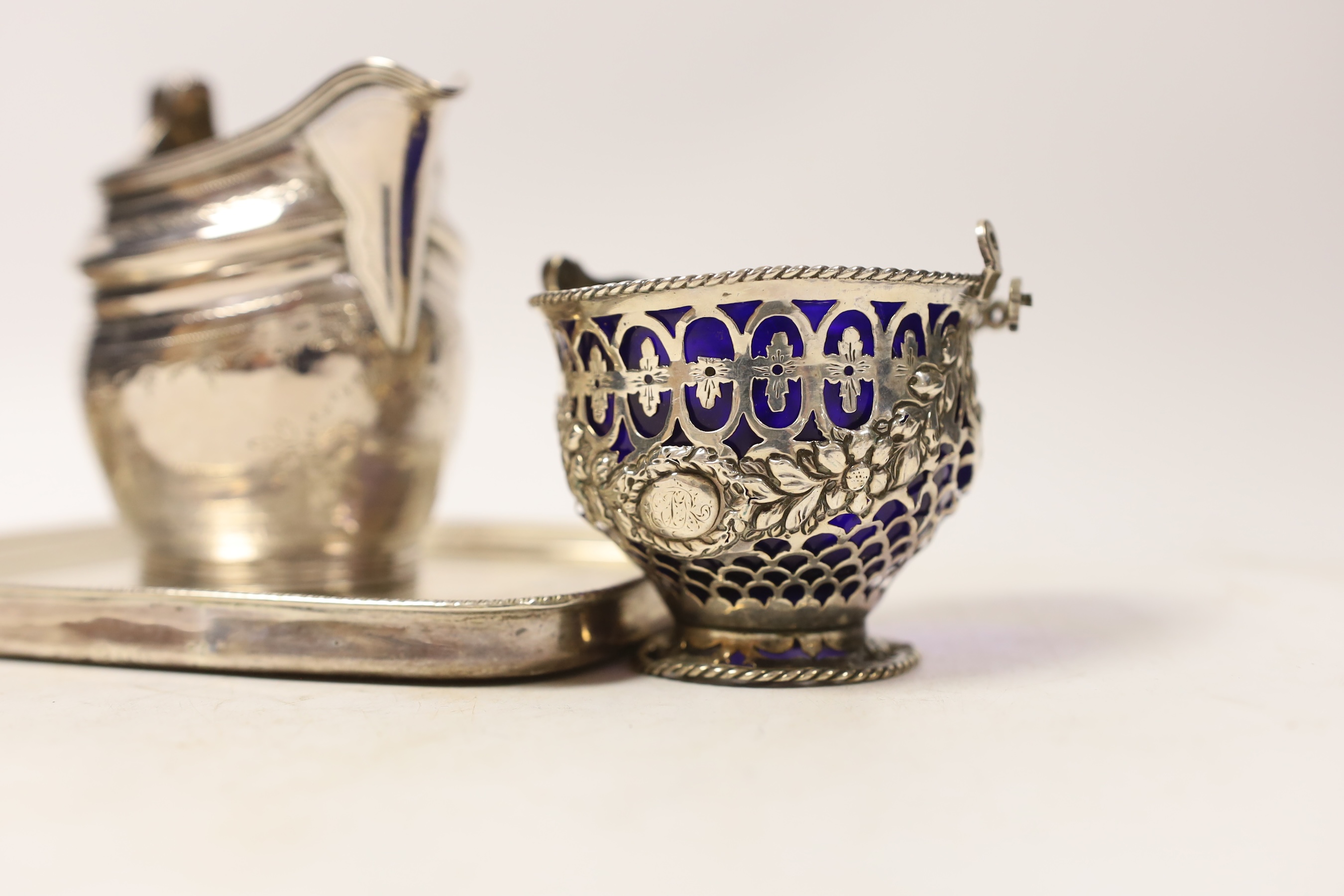A George III engraved silver helmet shaped cream jug, London, 1801, height 10.5cm, a small George III pieced silver sugar basket? (liner a.f.), London, 1770, a George III silver mounted teapot stand, London, 1808 and a s